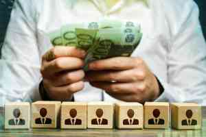 Figuren auf Würfeln und Hände mit Geldscheinen