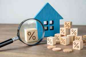 Lupe, Holzhaus und Würfel mit Prozentzeichen